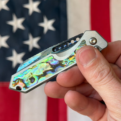 Heretic Knives Jinn Manual Knife – Titanium Chassis, Vegas Forge Herringbone Damascus, Hand Ground Blued Blade, Abalone Inlays – Serialized – Made in USA (S/N 013)